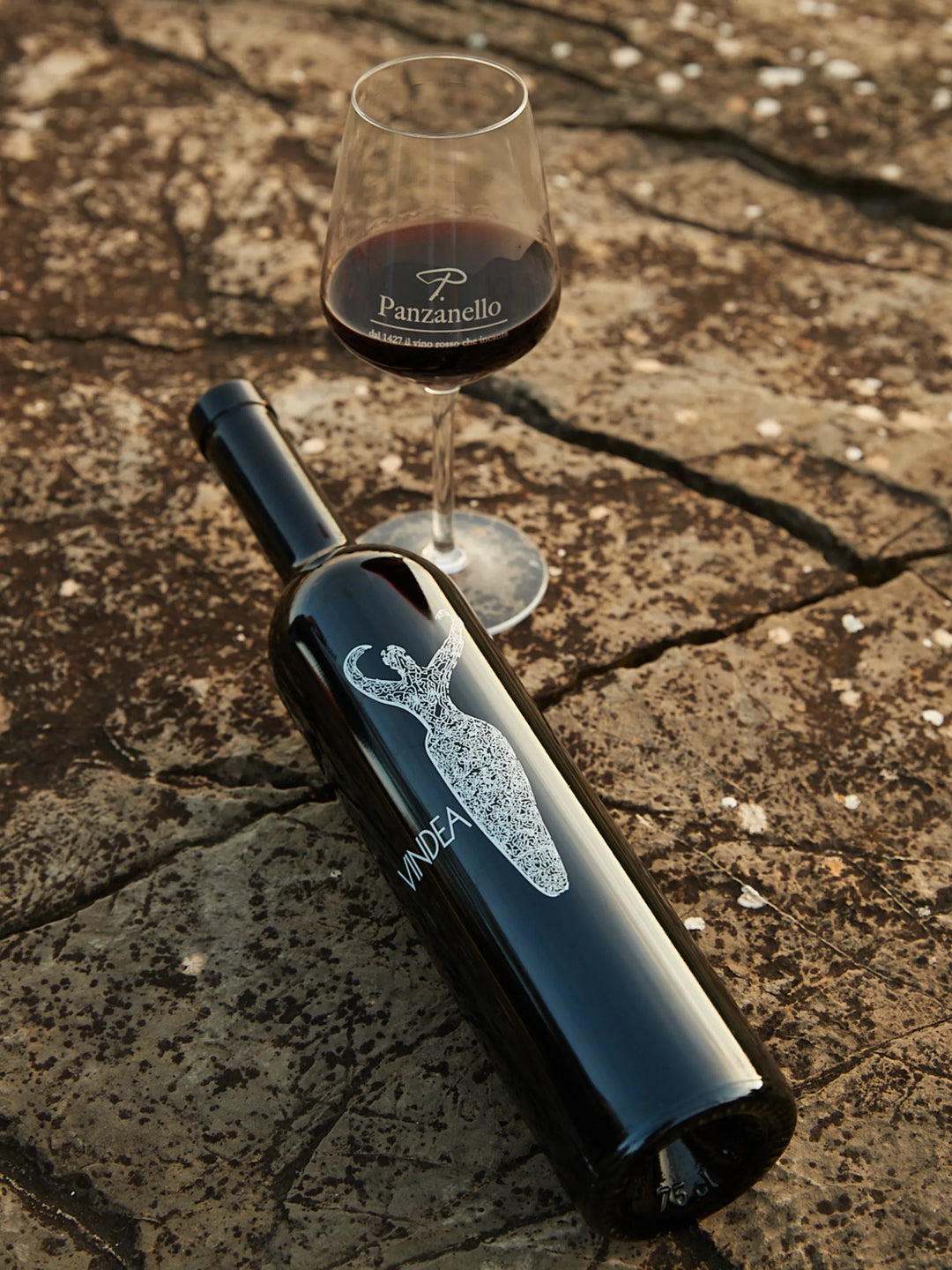 Vindea Supertuscan Panzanello 2015 disteso su pietra con calice riempito, vino pregiato IGT toscano in edizione limitata da collezione